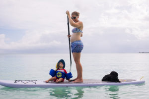 Pregnant woman on a stand up paddle board with her child and dog